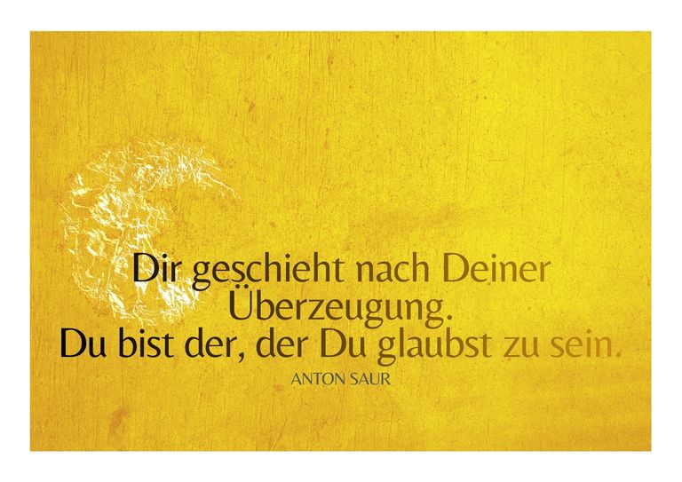 Gelber Hintergrund mit einem sich auflösenden weißen Muster links und einem Zitat von Anton Saur in schwarzer und brauner Schrift: "Dir geschieht nach Deiner Überzeugung. Du bist der, der Du glaubst zu sein."